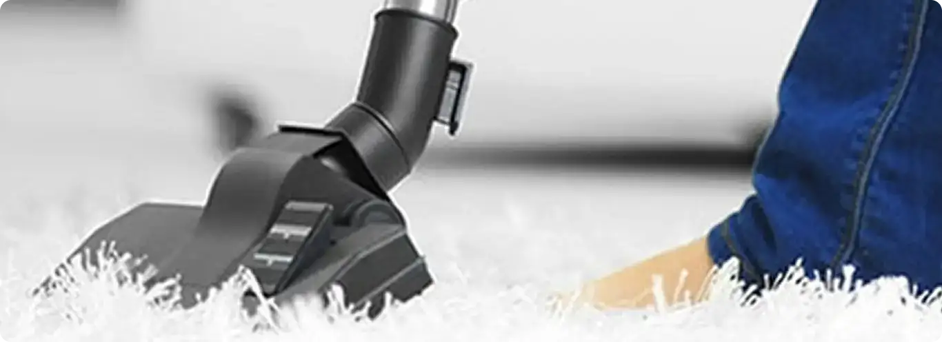 Close-up of a professional vacuuming a white carpet in Sunshine.